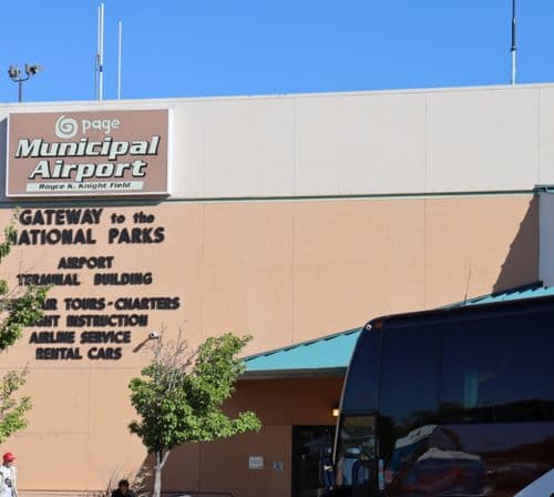 Black tour bus in front of Page airport sign