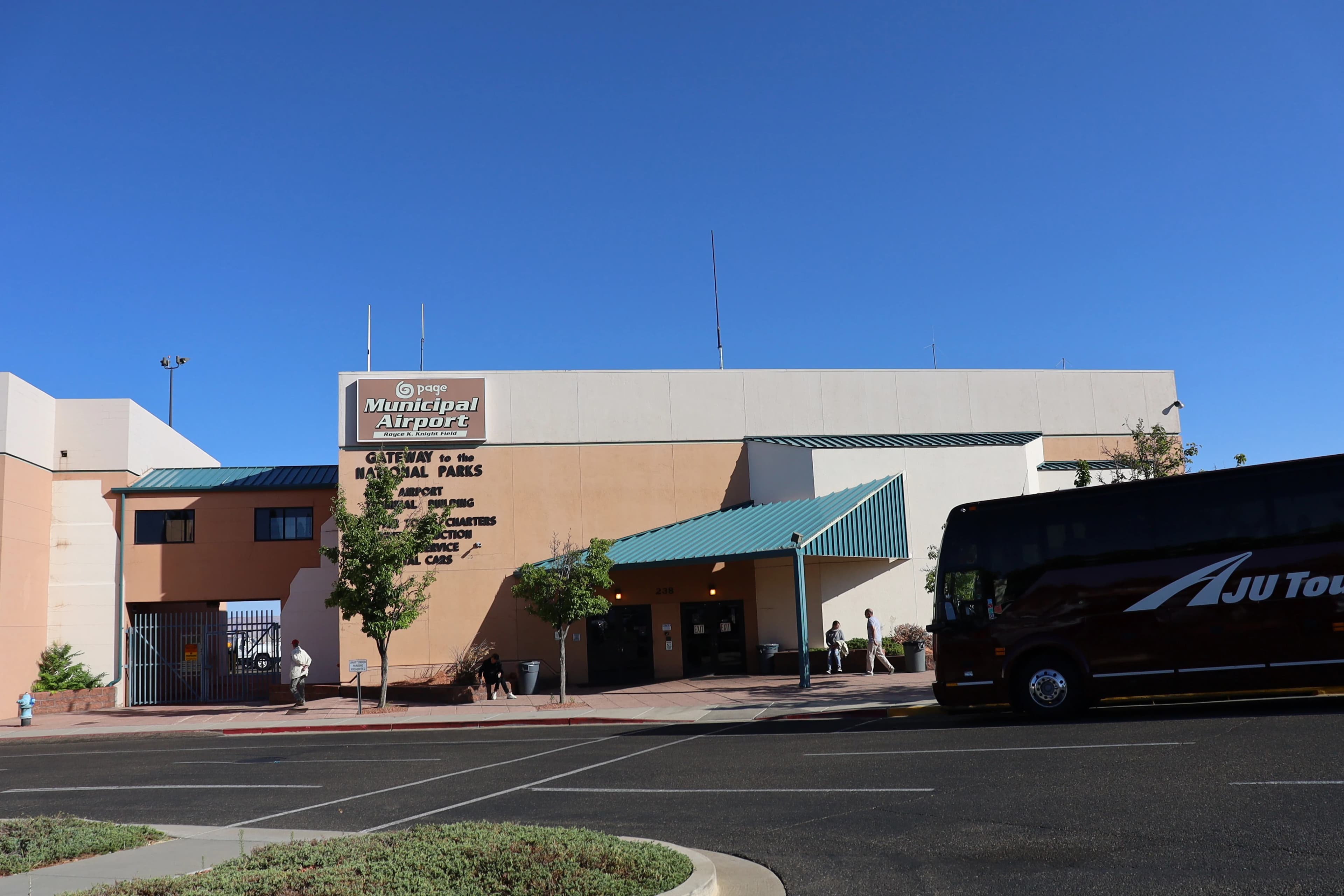 Black tour bus in front of Page airport sign